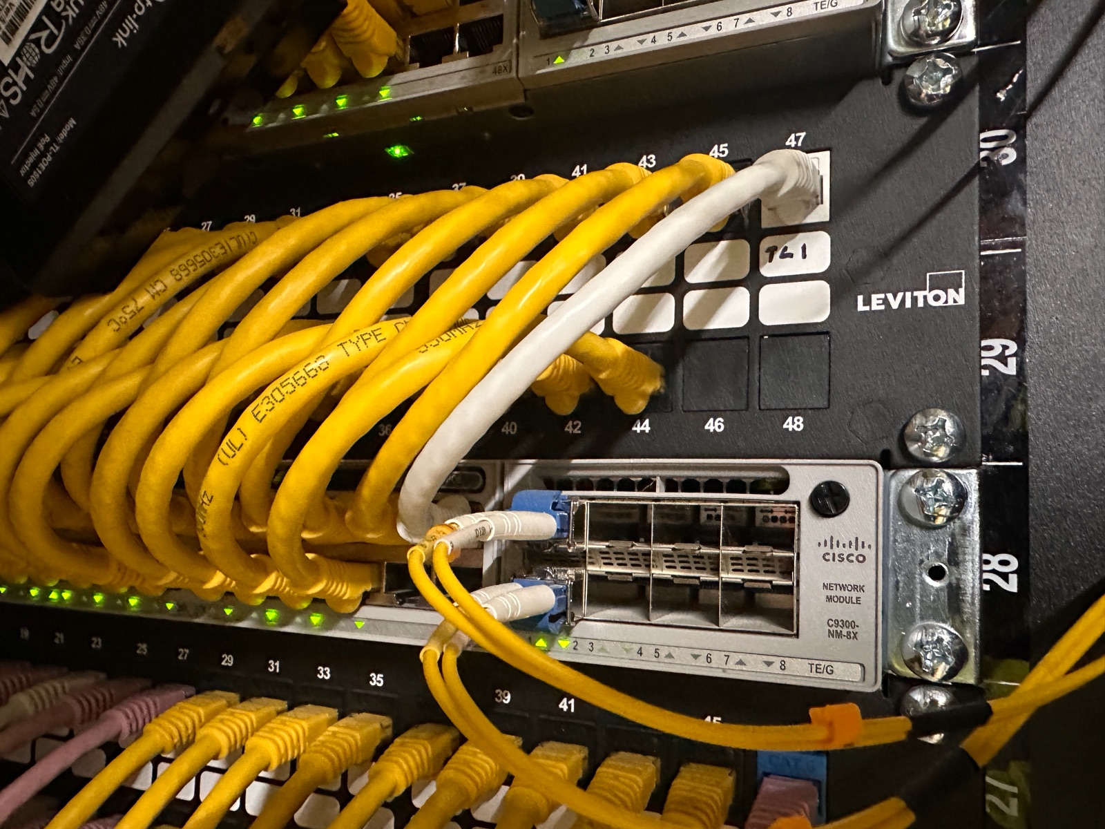 Cat6 runs terminated into a patch panel above a Cisco C9300 switch in an IDF cabinet